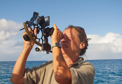 navigator on board of a sailing yacht using a sextant as traditional method of navigation