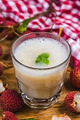 Litchi juice in a glass. Fresh juicy lychee fruit on a glass plate. Organic leechee sweet fruit.