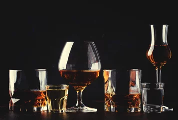 Foto op Plexiglas Alcohol Set van sterke alcoholische dranken in glazen en borrelglas in assortiment: wodka, rum, cognac, tequila, cognac en whisky. Donkere vintage achtergrond, selectieve focus