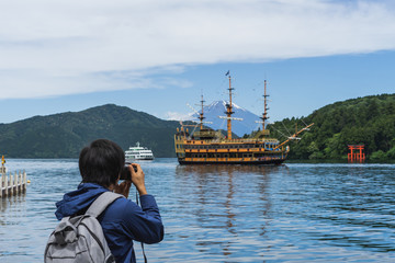 Young traveler takeing photo of  Hakone shrine with sightseeing cruise and mt.Fuji at  lake Ashi,...