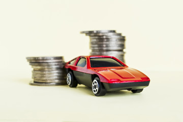 Red toy car rides up a stack of coins