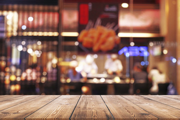 Empty wood table top with blurred light bokeh in night cafe restaurant background