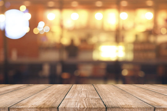 Empty wood table top with blurred light bokeh in night cafe or restaurant background