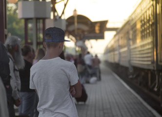 people are standing on a sunset sunset greeting the arrival of the train at the train station seeing off the tank top cap inscription copy space