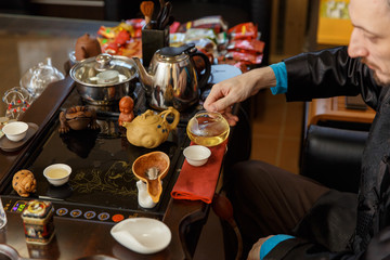 Chinese traditions. Master pours tea from a glass teapot