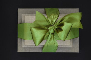 Three brown carton gift boxes bundled with green ribbon isolated on black background and view from above