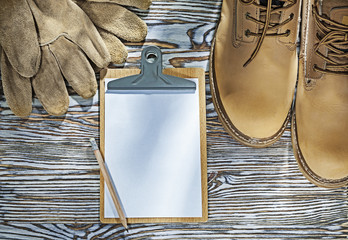 Safety boots gloves pencil clipboard on wooden board