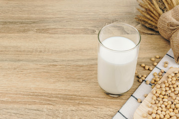 a glass of soy milk, a pile of soybeans and dried wheat bouquet on the wooden table.