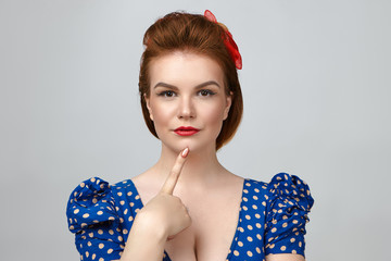 Picture of fashionable glamorous young red haired female dressed in pin up style posing isolated in...