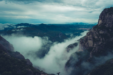 Obraz premium Mountains near Montserrat Abbey in Spain. Clouds and fog. Trees on cliffs.
