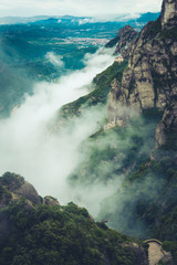 Mountains near Montserrat Abbey in Spain. Clouds and fog. Trees on cliffs.