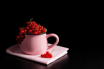 Redcurrant pile (ribes rubrum) pink cup pink napkin dark background