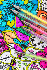 Adult coloring book, new stress relieving trend. Art therapy, mental health, creativity and mindfulness concept. Adult coloring page with pastel colored gel pens, Flat lay background.