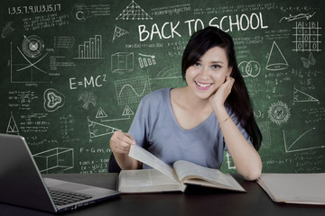 Female college student with book in the classroom