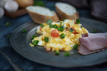 Scrambled eggs with tomatoes on dark background
