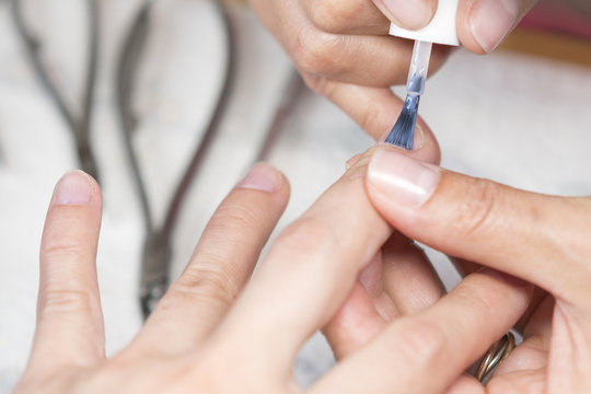 The beautician busy with the final touches of the manicure, putting on the cutex. Applying coat of nail varnish in beauty salon