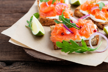 Smoked salmon sandwich with cream cheese on wooden table.
