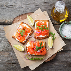 Smoked salmon sandwich with cream cheese on wooden table. top view