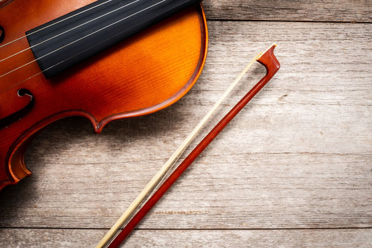 Brown violin with fiddle stick on wooden background. Art and music background.