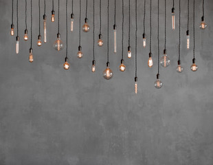 Edison retro lamp Incandescent bulbs on gray plaster wall background in loft. Concept Vintage...
