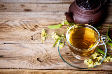 cup of  linden tea and teapot on wooden table