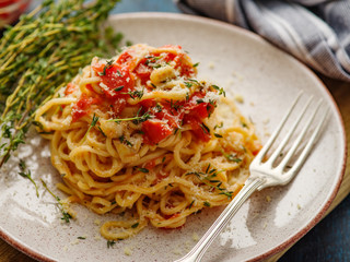 Spaghetti with tomatoes and thyme in a plate on a blue table