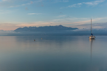 Fototapeta na wymiar Colorful sunrise on the marina of Lausanne on the Lake Leman in summer with the view of the Swiss Alps in background - 25