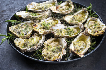 Barbecue overbaked fresh opened oyster with garlic and herbs offered as closeup on a tray