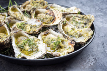 Barbecue overbaked fresh opened oyster with garlic and herbs offered as close up on a plate