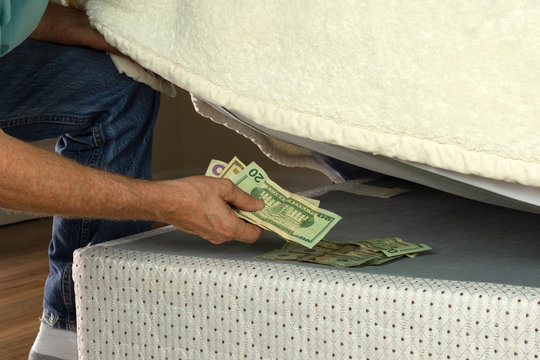 Man stashing putting money under his mattress because he doesn't trust banks and is fearful of financial institutions, this is a bad way to save your money for retirement. There must be a better way!