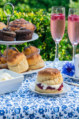 Afternoon tea with cakes and traditional English scones with strawberry jam and clotted cream set...