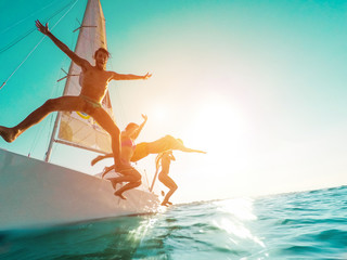 Happy crazy friends diving from sailing boat into the sea - obrazy, fototapety, plakaty