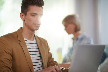 Obraz premium Manager in smart casual sitting in front of laptop and processing online data or preparing presentation