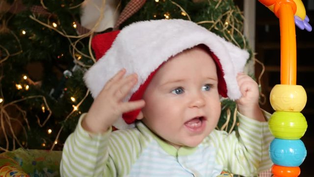 Baby tugs at Santa hat on his head
