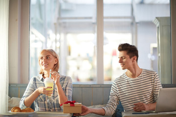 Young man making surprise for his girlfriend while spending time in cafe on valentine day