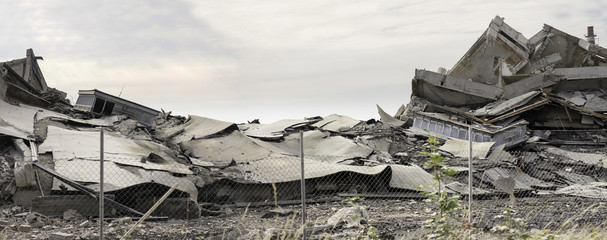 Industrial concrete building destructed by strike. Disaster scene full of debris, dust and crashed...