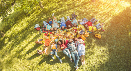 Happy friends lying down at picnic dinner outdoor