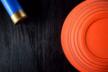 Flying target plate for shotgun sport against the dark wooden background. Copy space