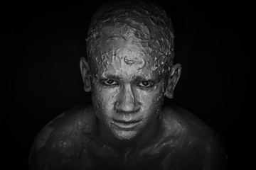 Close-up of a man's face in clay. Monochrome portrait 