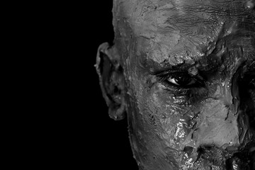 Close-up of a man's face in clay. Monochrome portrait 