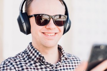 Young man with modern, good quality headphones connected to his smartphone