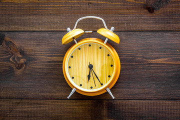 Alarm clock for for waking up on dark wooden background top view copy space