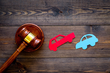 Car accident lawsuit concept. Two collided cars near judge gavel on dark wooden background top view...