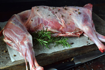 Whole raw lamb and knife on the wooden board. Sheep carcass with fresh herbs, spices. Raw meat....