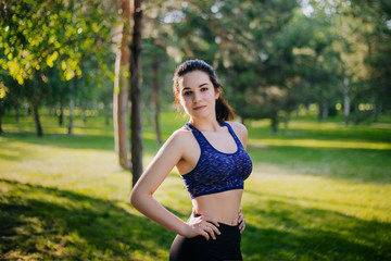 A beautiful girl in the park is engaged in sports. A model with clean skin and oboyatelnoy ulvbkoy in sportswear. Open-air trainings.