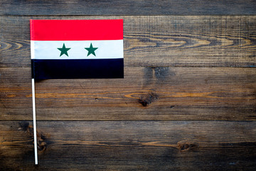 Syrian flag concept. small flag on dark wooden background top view copy space