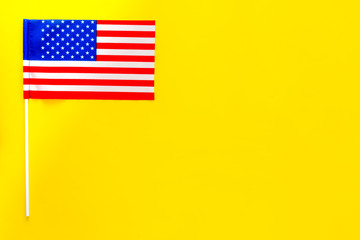 American flag concept. Small flag on yellow background top view copy space