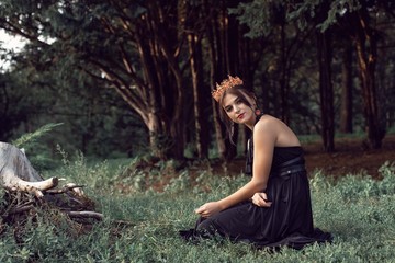 Slender brunette in a black dress in the park
