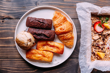 Fresh baked goods on white dish including scone, croissant, financier and chocolate financier.