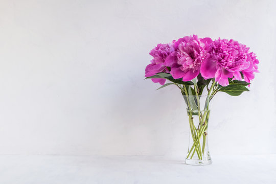 Pink peonies in a vase on a light background